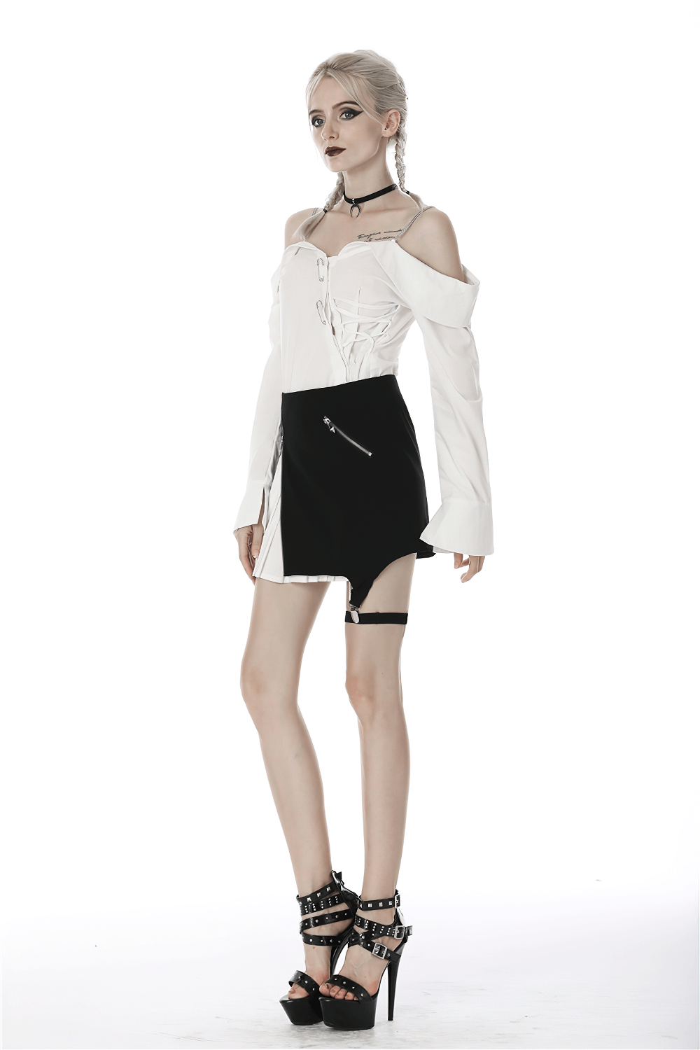 Edgy model showcasing black and white punk mini skirt with leg loop zipper and dramatic pleats.