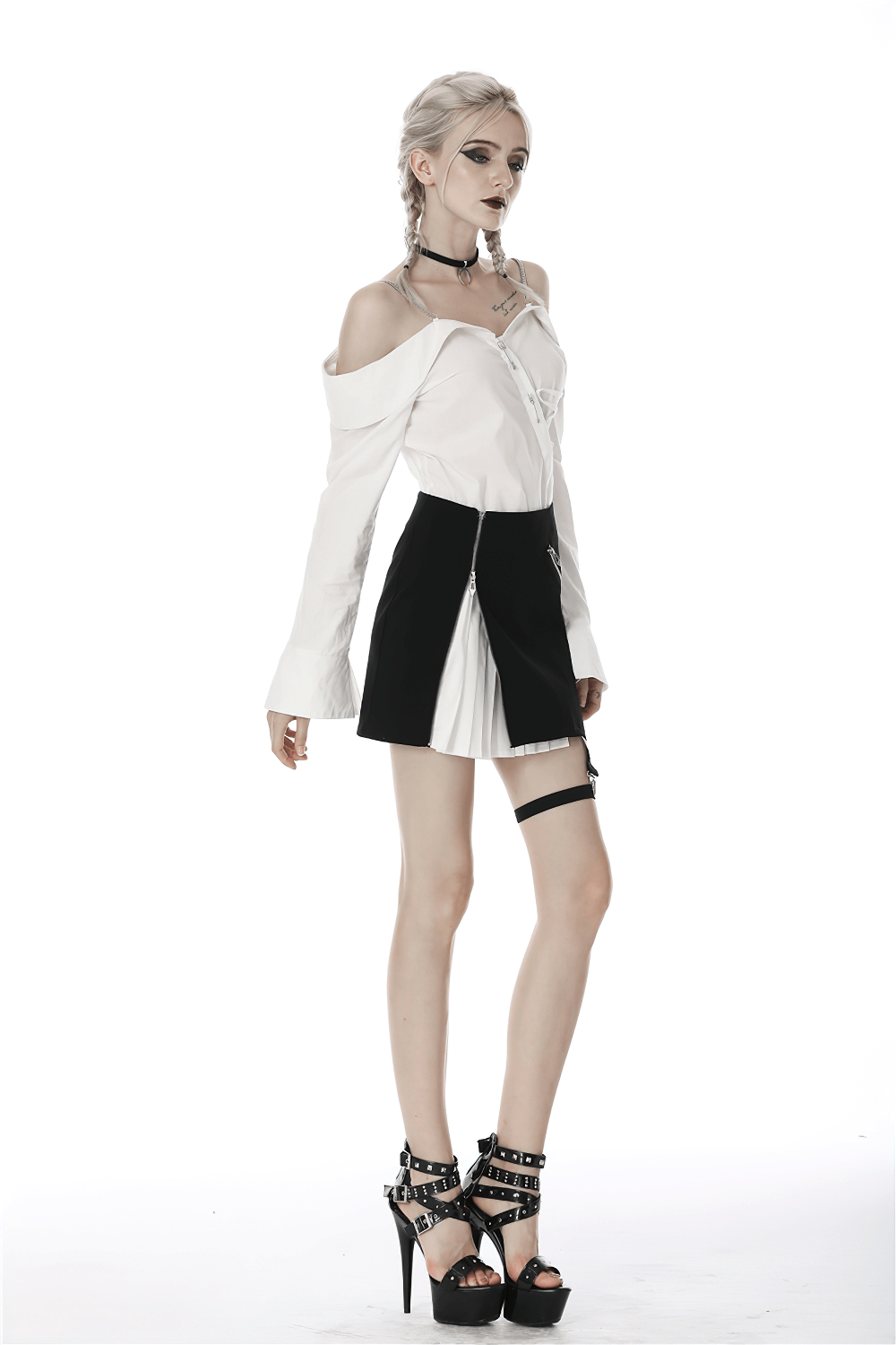 Punk-inspired black and white pleated mini skirt with leg loop zipper, modeled by a woman in edgy fashion.