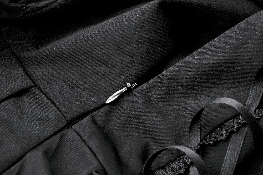 Close-up of black fabric with lace detailing and adjustable ribbons on a gothic dress.
