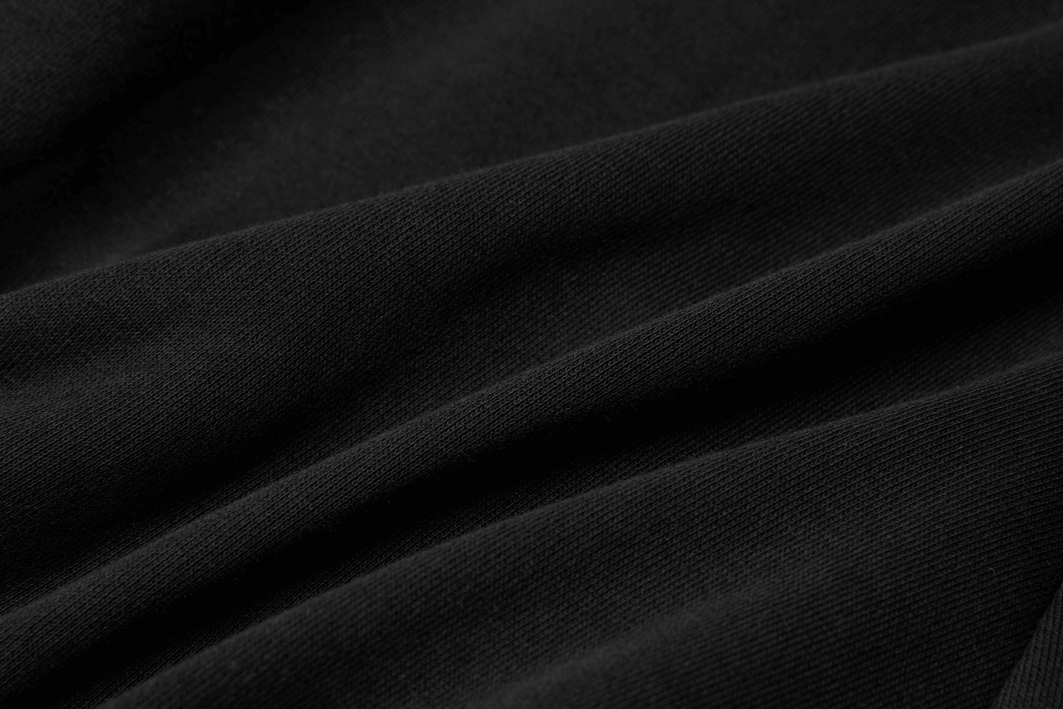 Close-up of soft black knitted fabric, showcasing its texture and depth, perfect for chic stylish garments.