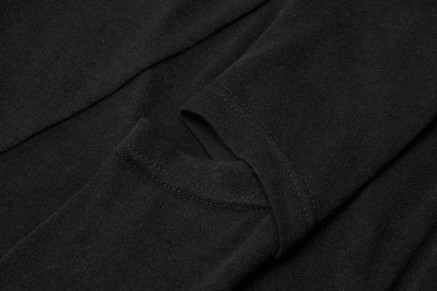Close-up of sleeve cut-out detail on a chic black knit dress, showcasing the stylish asymmetric design.