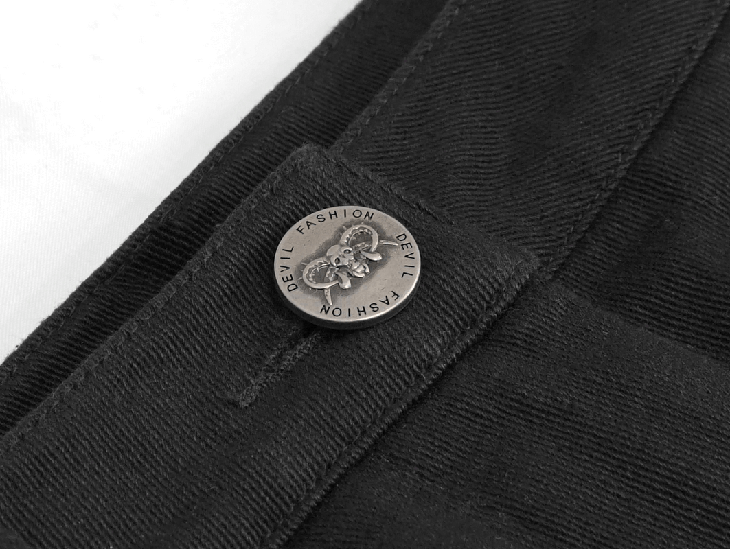 Close-up of a black asymmetrical pant's stylish button featuring a skull design, showcasing gothic fashion elements.