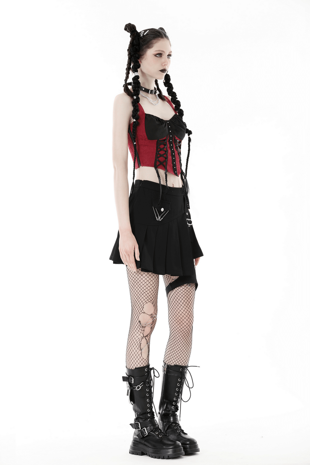 Model showcasing a black asymmetrical pleated skirt with safety pins, paired with a red corset and combat boots.