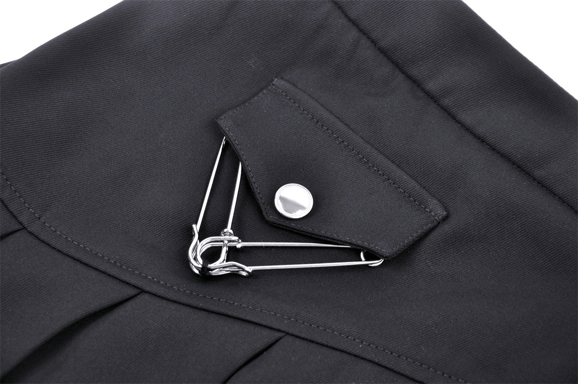 Close-up of black pleated skirt featuring edgy safety pin detail, adding punk flair to your outfit.