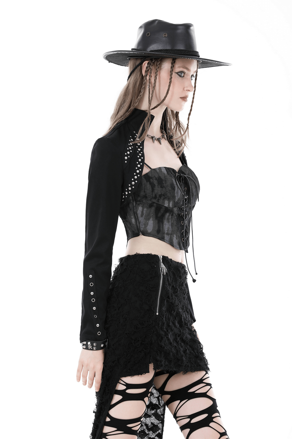 Fashion model wearing a black bolero with bead embellishments and a wide-brim hat, showcasing edgy evening wear.