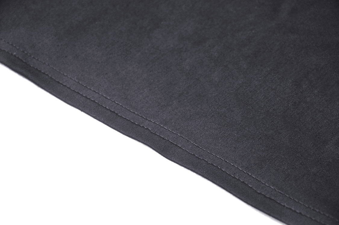 Close-up of the edge of a black fabric showing neat stitching, ideal for a bolero or evening wear.