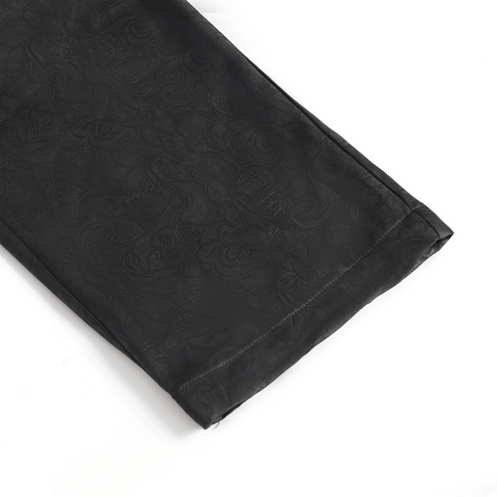 Close-up of black brocade gothic pants showcasing intricate embroidered details on fabric.