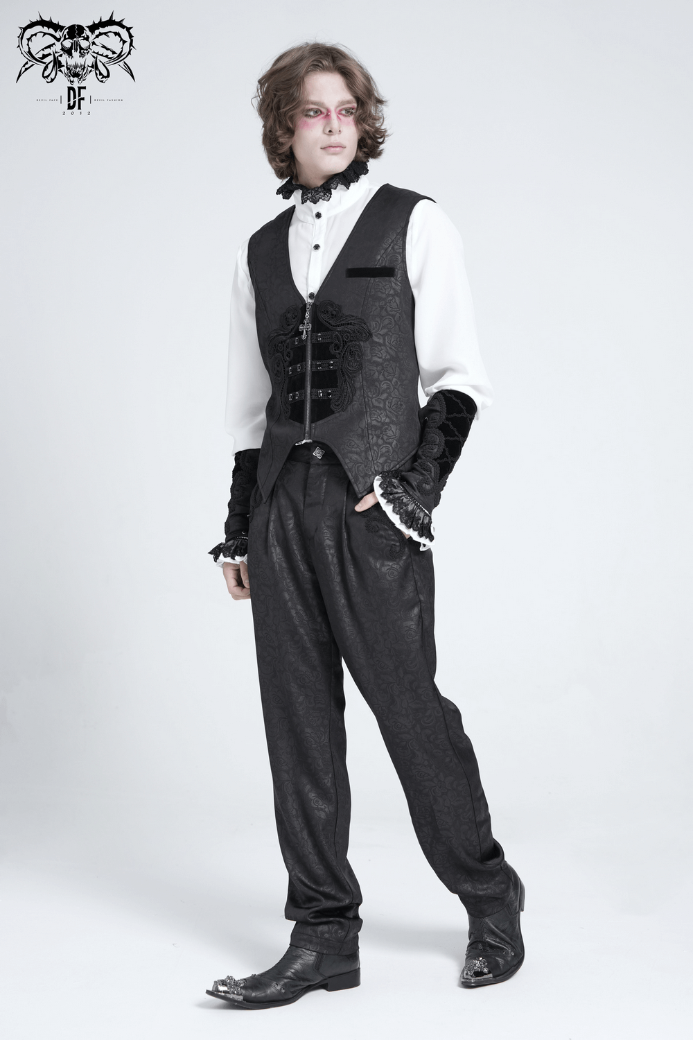 Man wearing black brocade gothic pants and an embroidered vest, embodying a stylish gothic aesthetic.