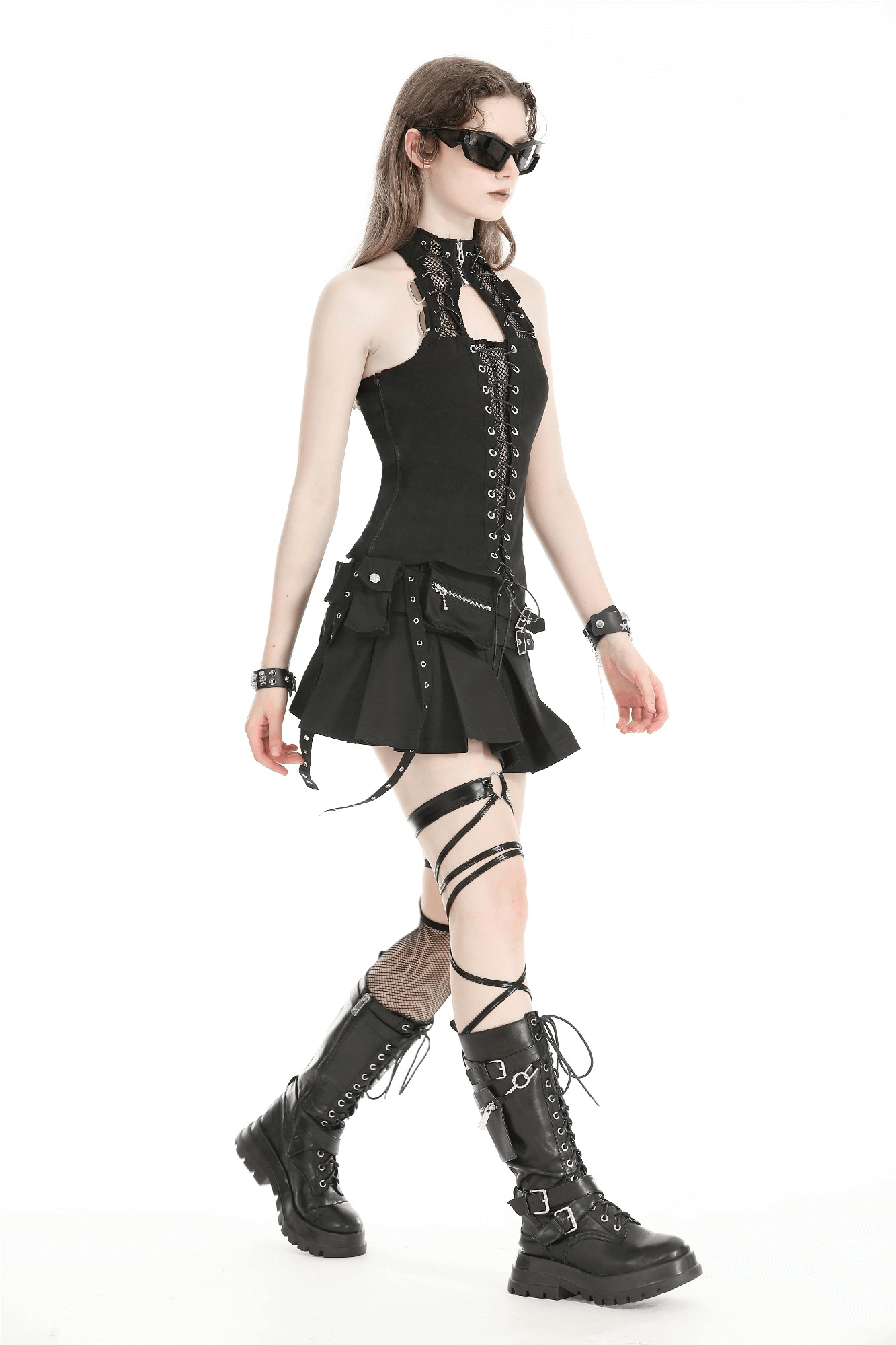 Chic model in black buckle mini skirt with side zipper, wearing edgy boots and stylish sunglasses, showcasing a bold alternative look.