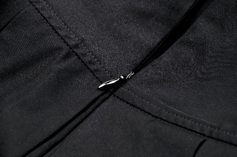 Close-up of the side zipper detail on a black pleated skirt with stylish buckle accents.