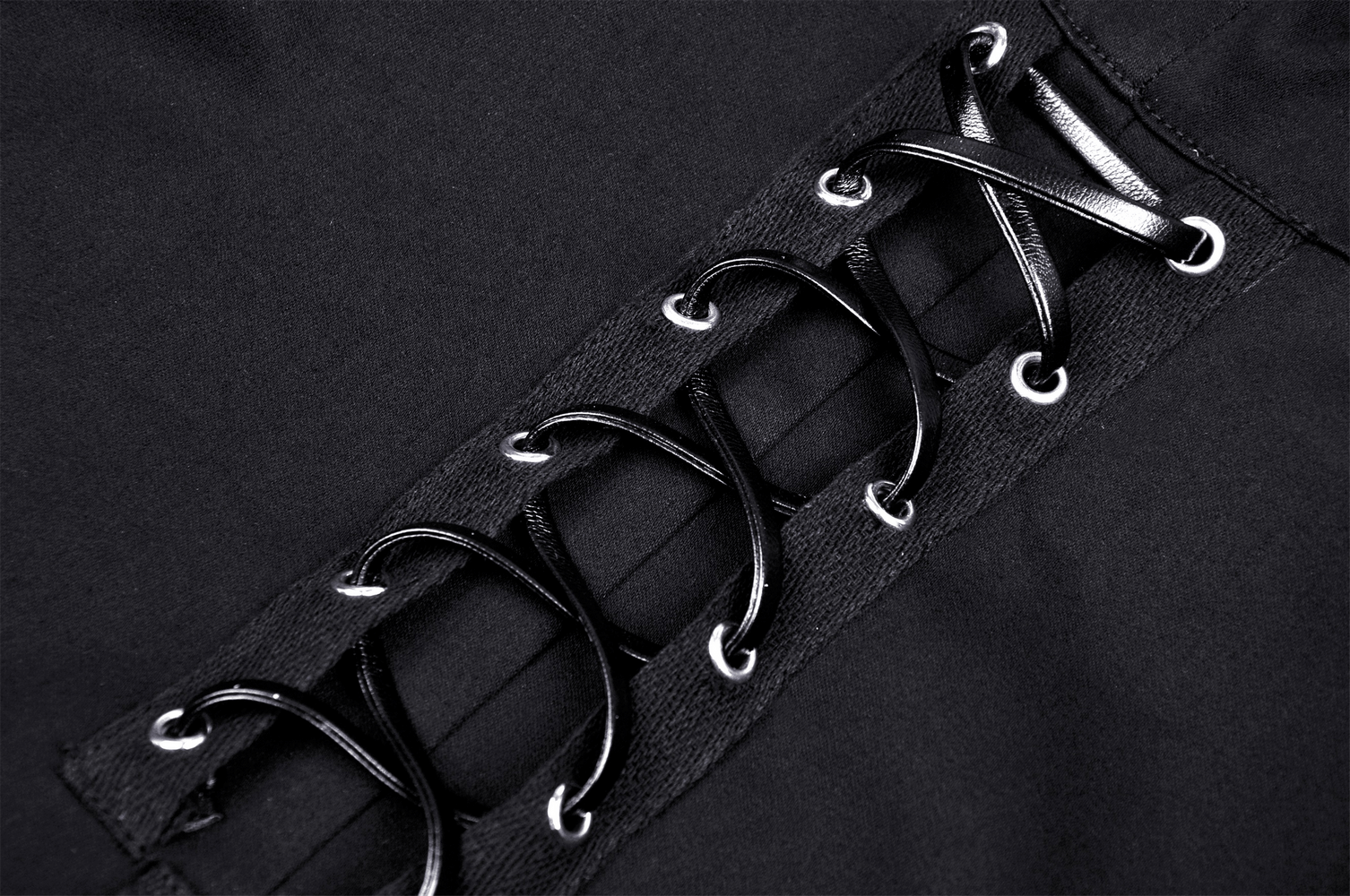 Close-up of black lace-up detail on gothic crop top, showing edgy design with shiny eyelets and ribbons.