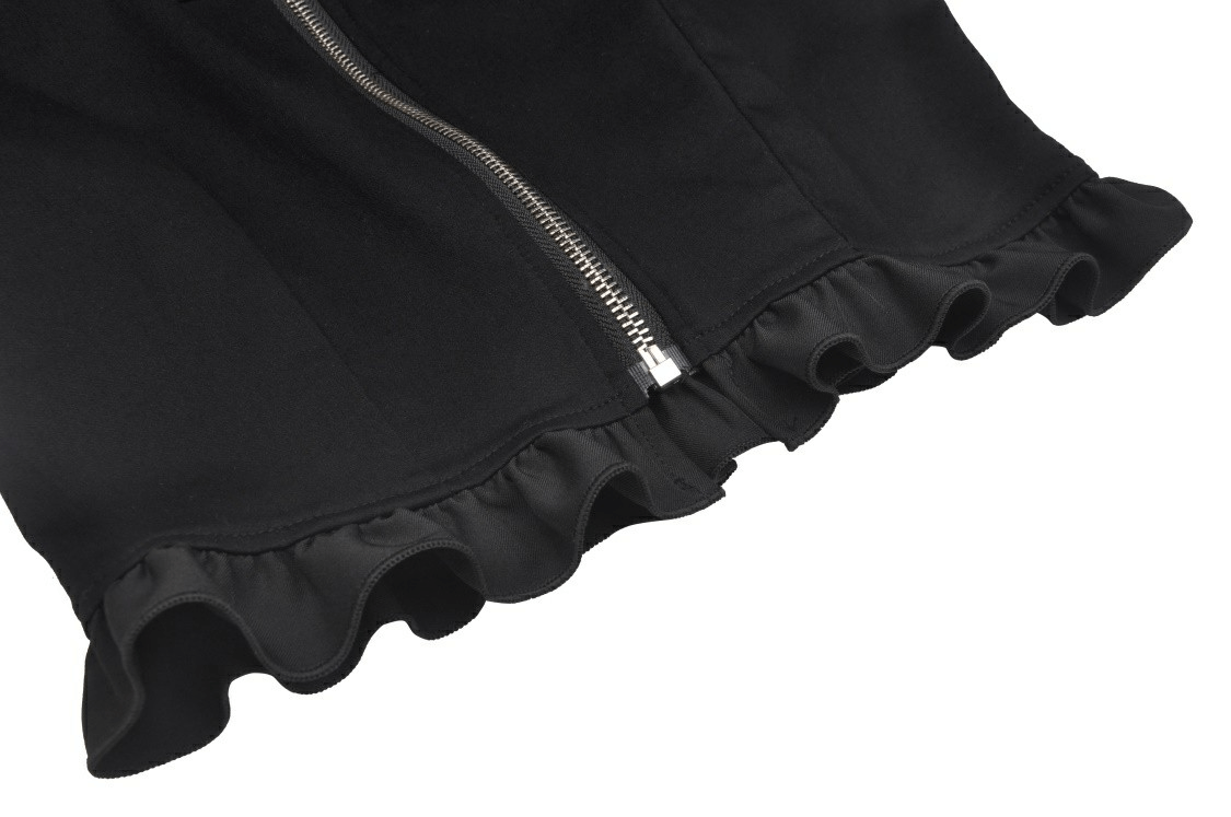 Close-up of the ruffled hem and zipper of a black crop top, showcasing its stylish design and playful details.