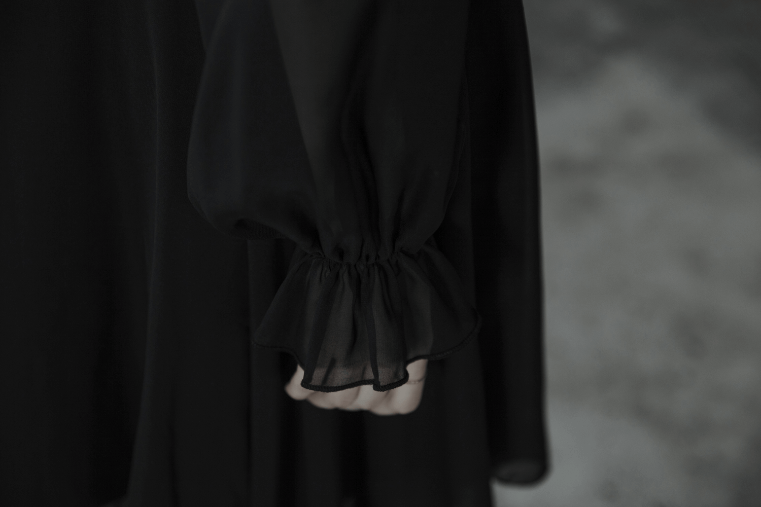 Close-up of the elegant puffed sleeve of a black chiffon dress, showcasing delicate ruffled cuffs.