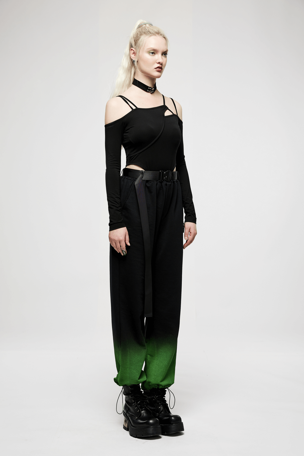 Model showcasing an edgy black choker neck bodysuit with long sleeves and unique green ombre pants.