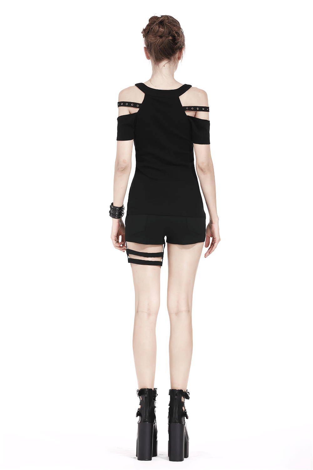Back view of a black cold shoulder gothic top with studded straps, paired with shorts and edgy boots.