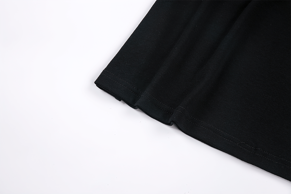 Close-up of the hem of a black cold shoulder gothic top with rivet strap details.