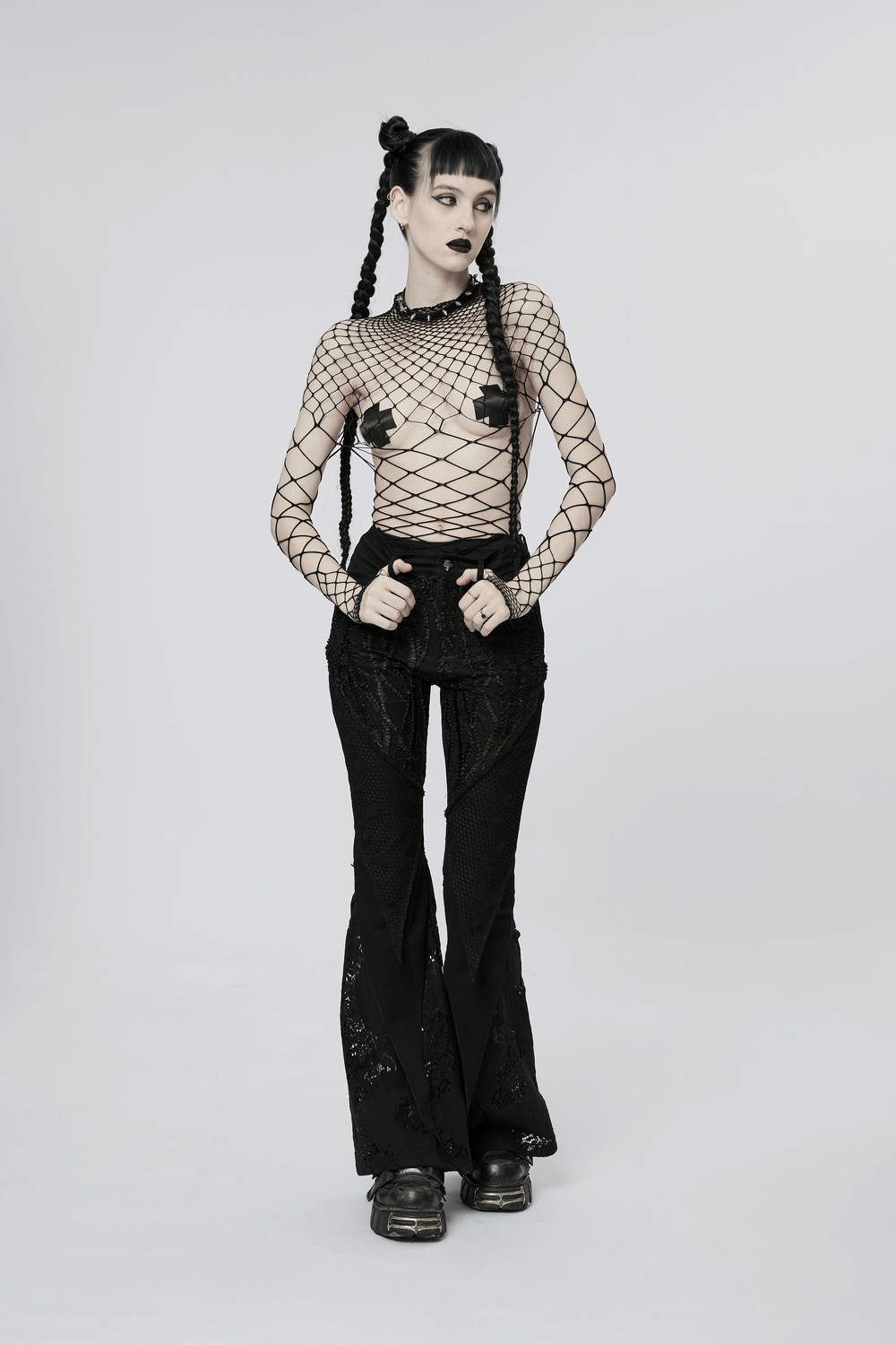 Model wearing a black diamond mesh bodysuit with flared black pants, showcasing edgy punk style and bold fashion.