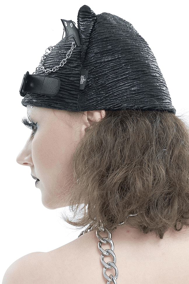 Side view of a woman wearing a black batwing buckle hat with chains and pins in a gothic style.
