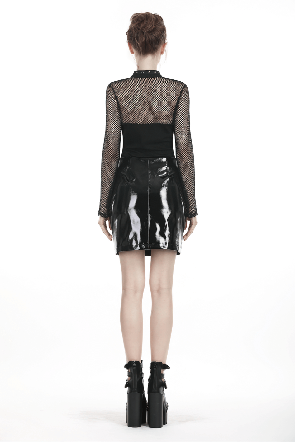 Back view of a model wearing a black faux leather mini skirt with a mesh long-sleeve top and edgy platform boots.
