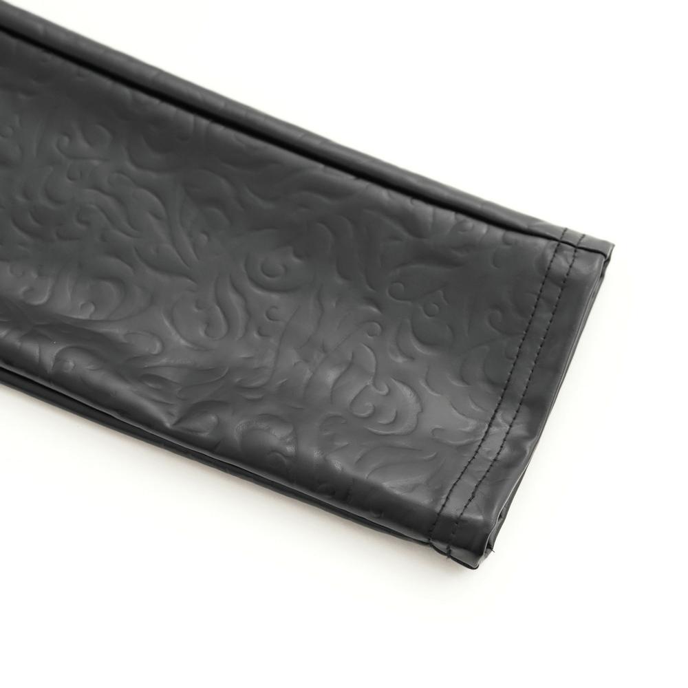 Close-up of textured black faux leather fabric with intricate patterns, ideal for edgy gothic fashion.