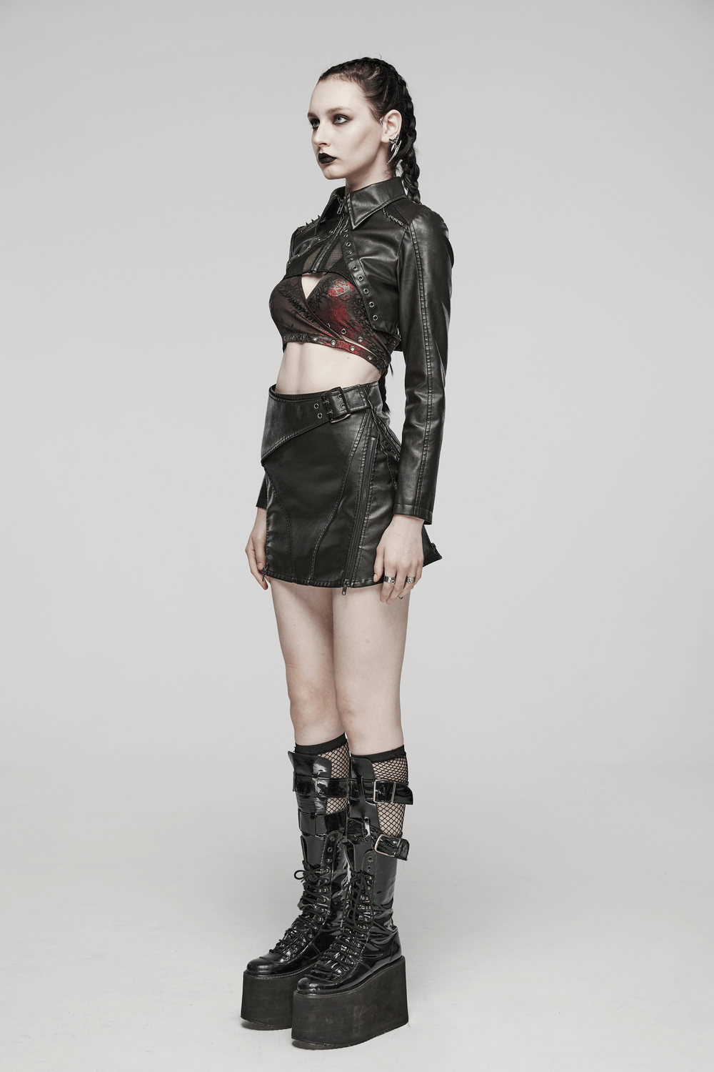 Model showcasing a black faux leather punk jacket with mesh accents, styled with a mini skirt and bold platform boots.