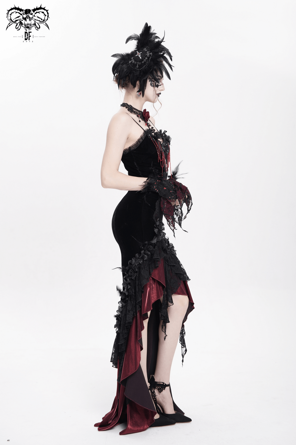 Gothic model in elegant black and red dress with feathers, lace details, and dramatic silhouette.