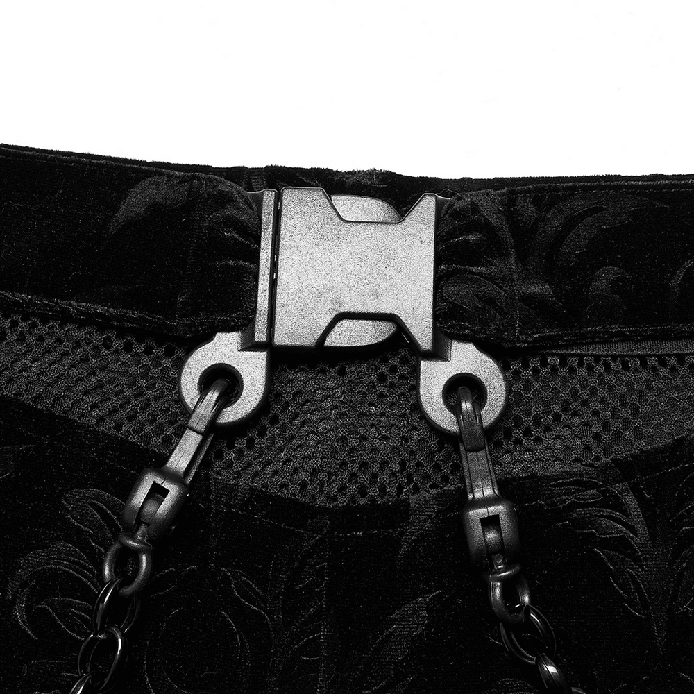 Close-up of the mesh waistband and metal chain details on black floral velvet flared pants.