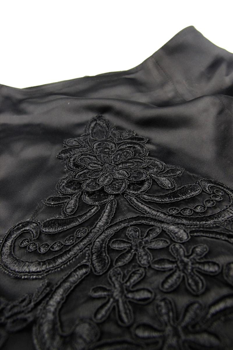 Close-up of black fabric with intricate floral lace embroidery, showcasing gothic elegant style details.