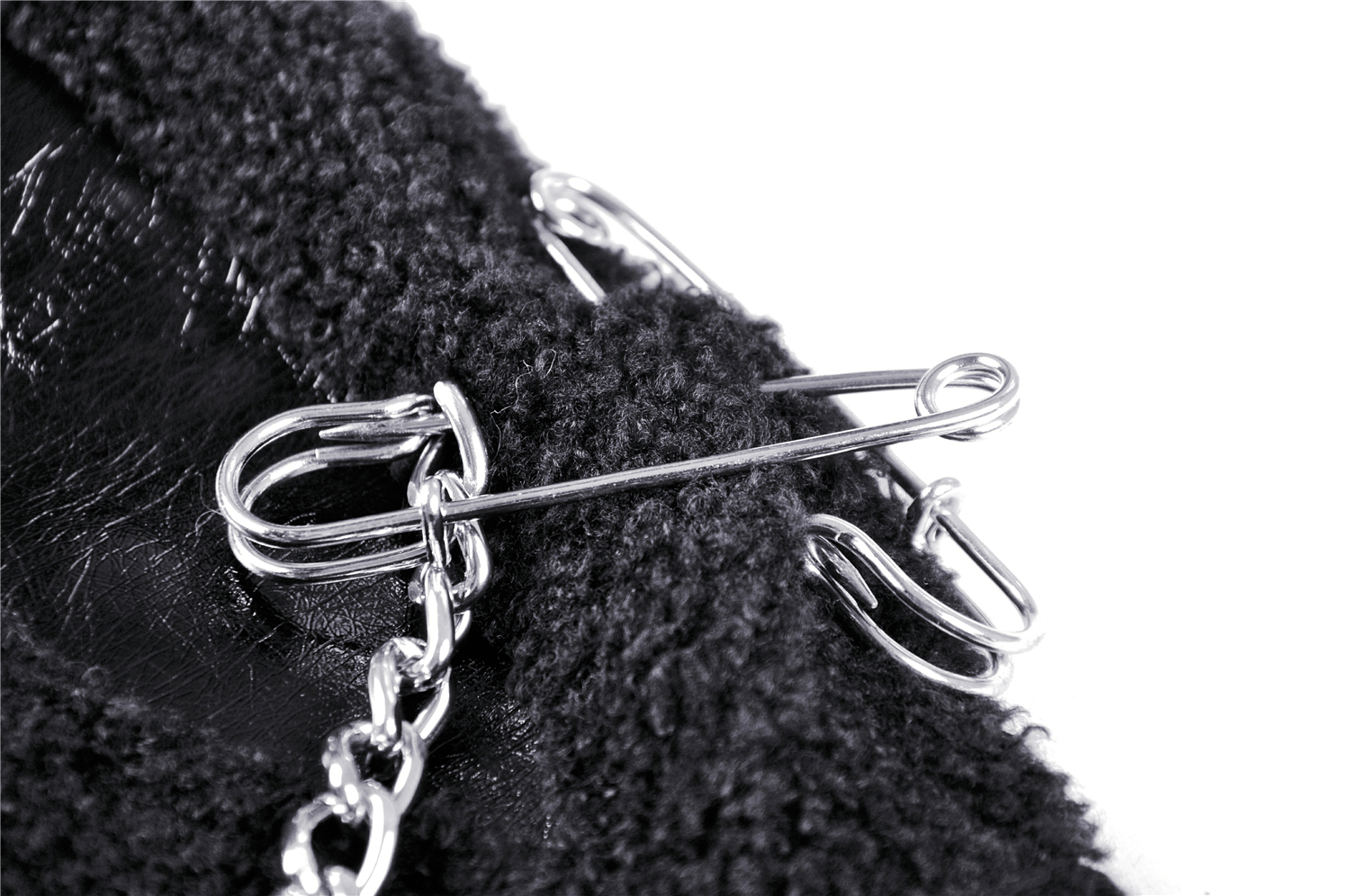 Close-up of a black gothic scarf featuring chains and safety pins for a punk look.