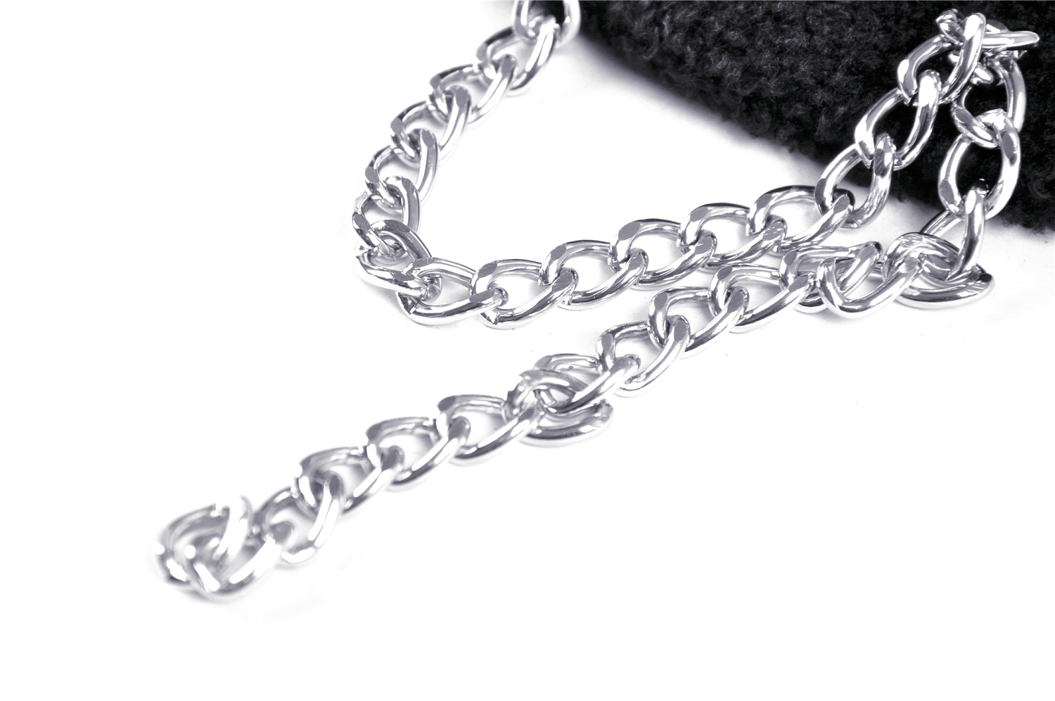 Close-up of a shiny silver chain accent on a black scarf, perfect for gothic or punk fashion styles.