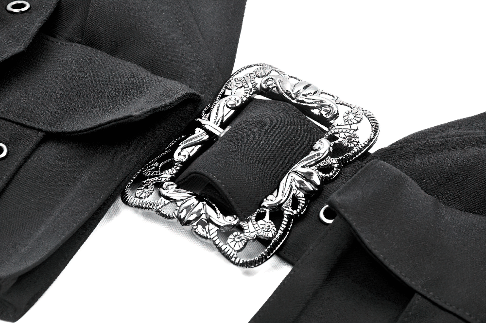 Close-up of silver baroque buckle detail on black gothic crop top with straps and grommet embellishments.