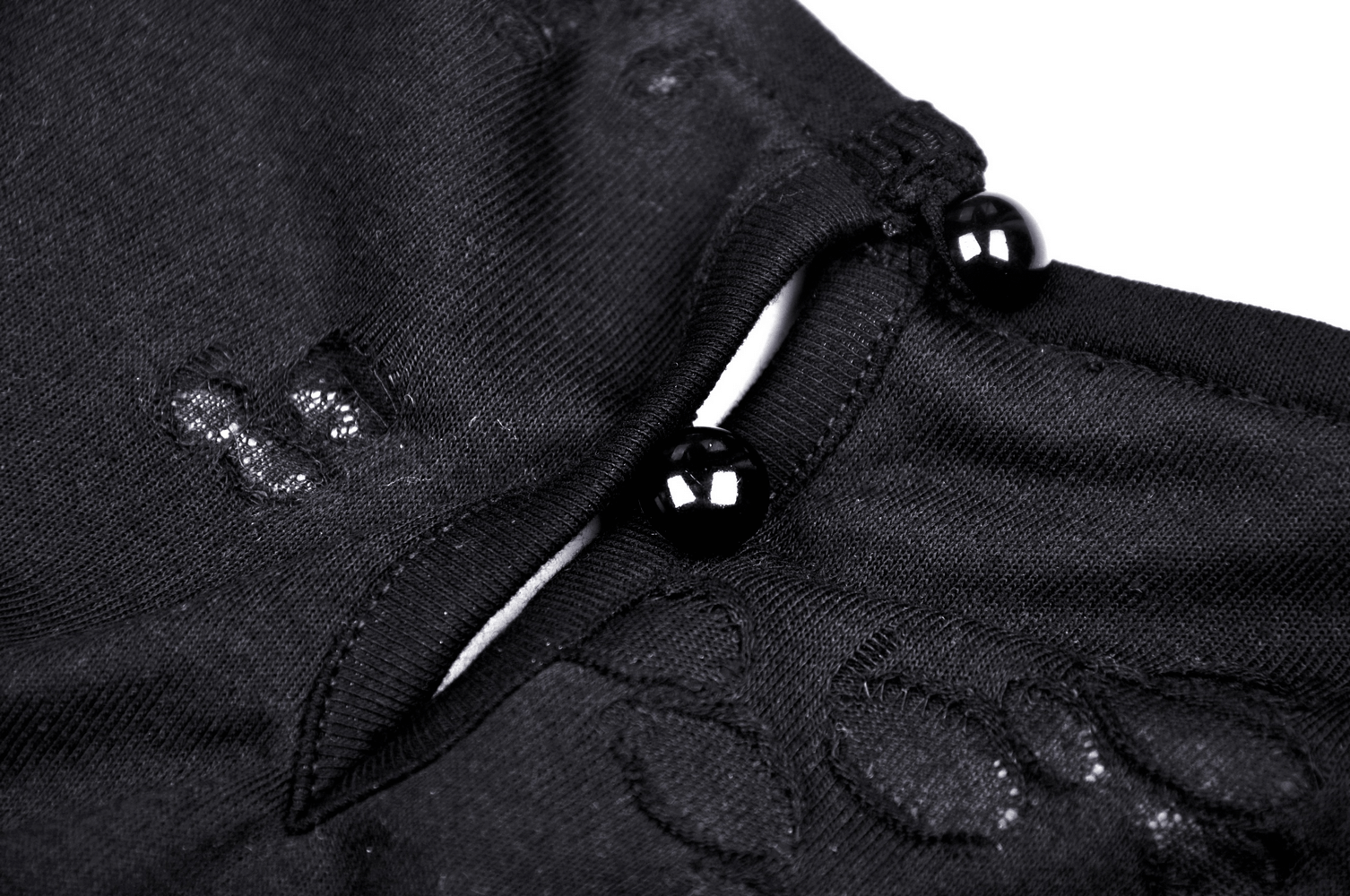 Close-up of black Gothic crop top's chain strap detail with glossy buttons, perfect for edgy style.