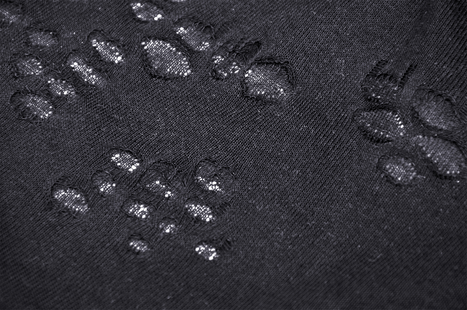 Close-up of a textured black fabric with subtle paw print designs, showcasing edgy style and softness.