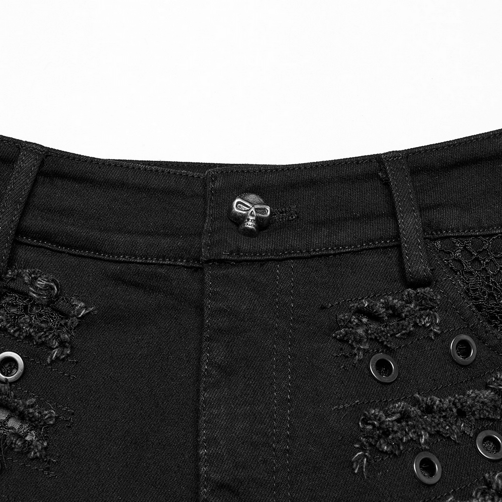 Close-up of black gothic distressed denim shorts featuring eyelets and unique skull button detail.
