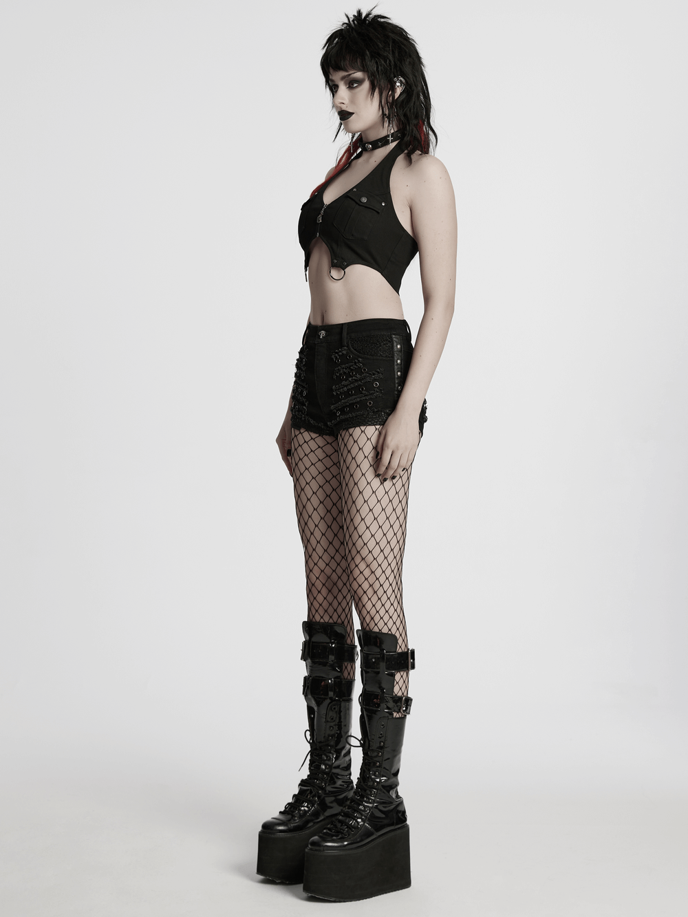 Stylish model in black gothic distressed denim shorts with eyelets, paired with fishnet tights and platform boots.