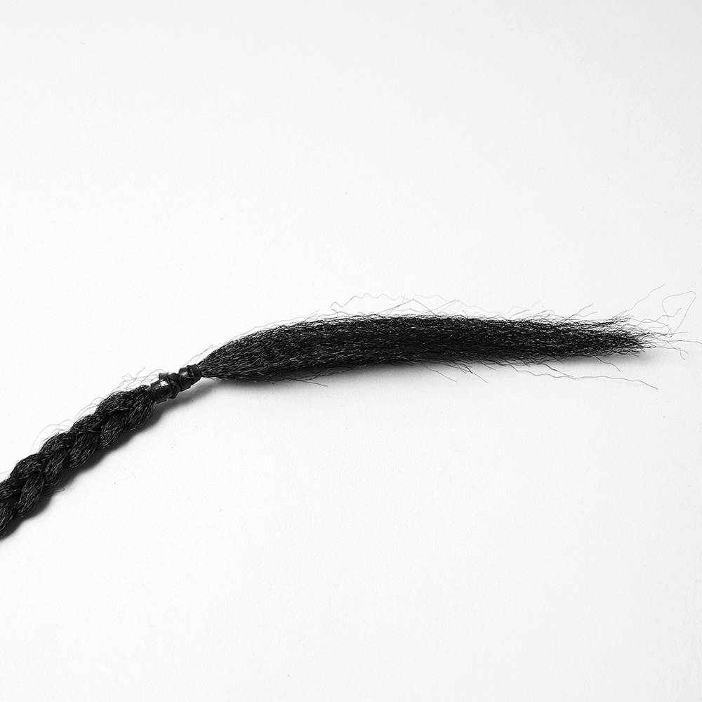 Close-up of black braided hair accessory strand with a frayed tip, perfect for gothic or punk styles.
