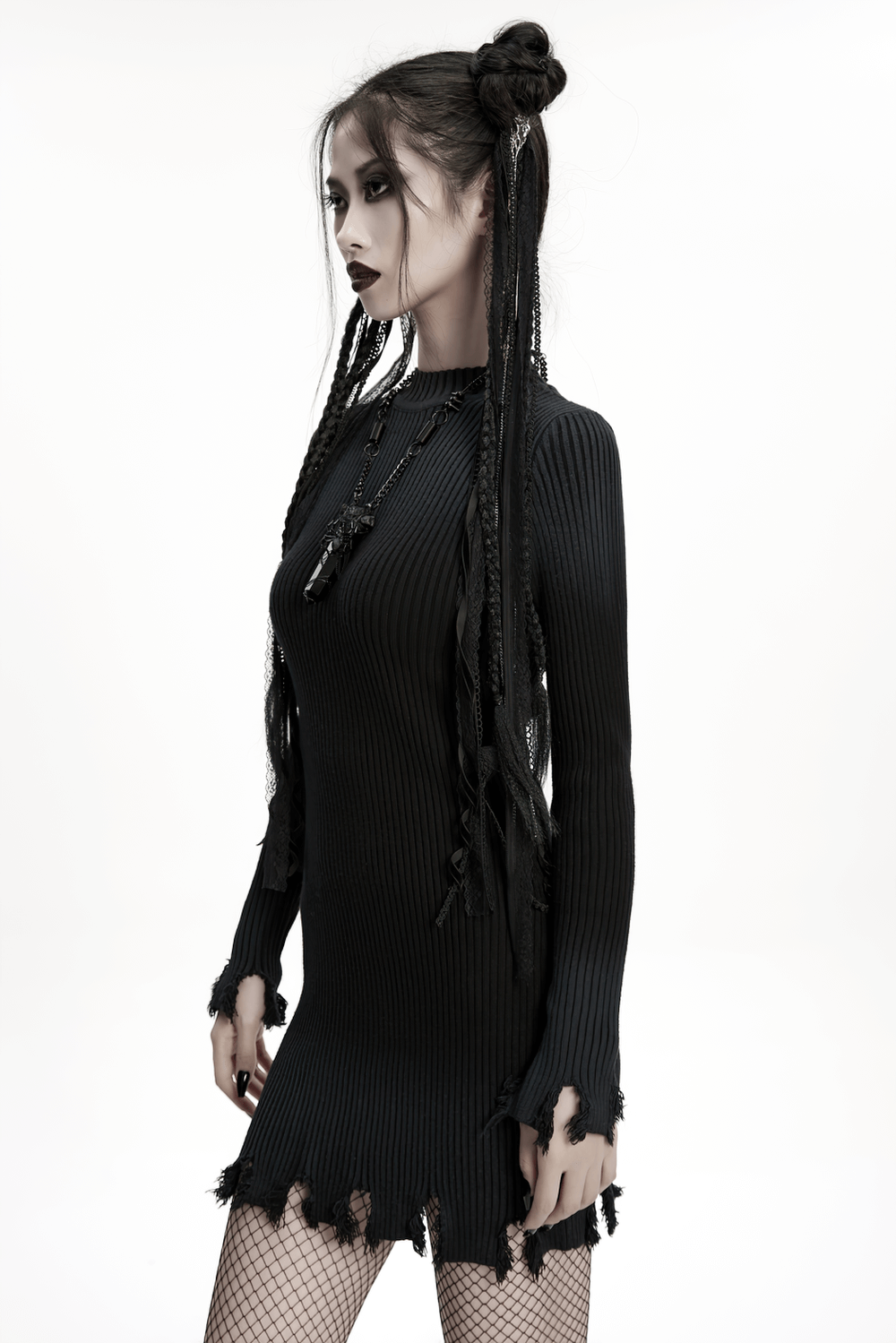 Model in black ripped dress showcasing gothic style with dramatic hair and accessories.