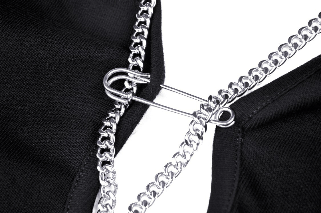 Close-up of black gothic halter crop top featuring edgy chain detail and safety pin embellishment.