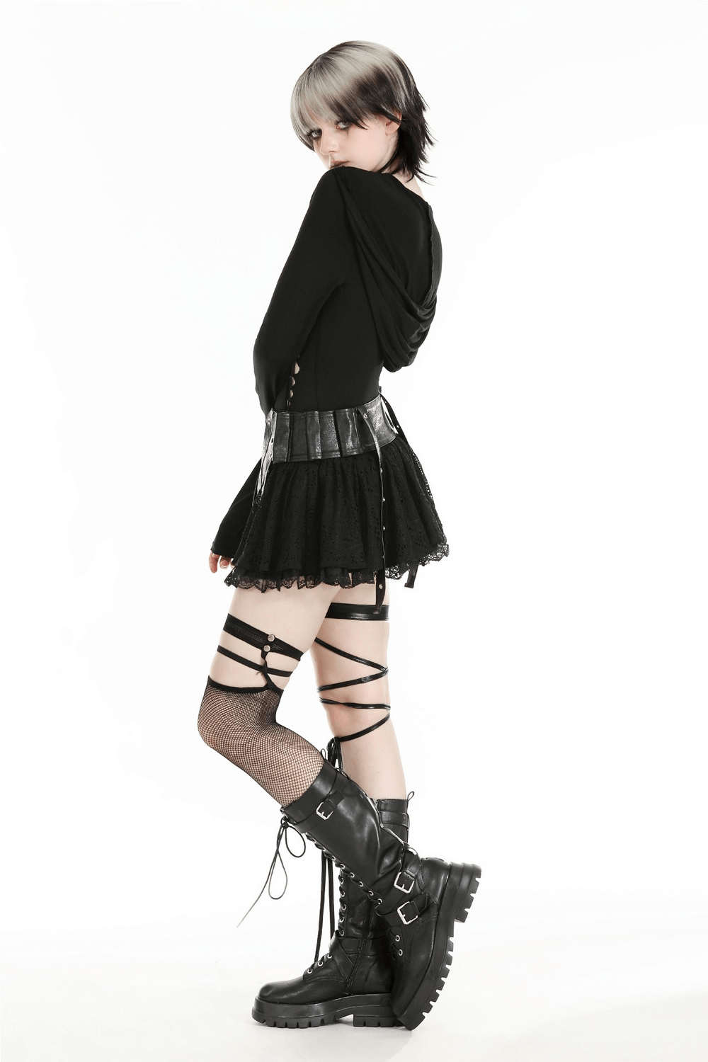 Woman in black gothic hooded top and skirt with edgy accessories and boots, embodying alternative fashion style.