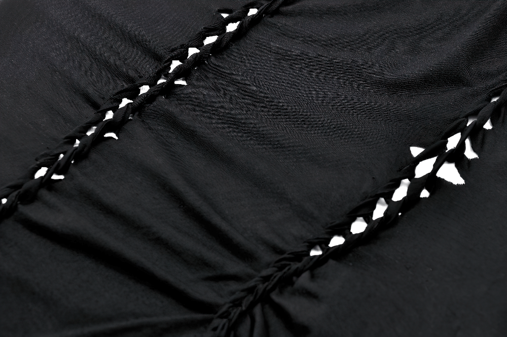 Close-up of black fabric with intricate braided cutout design and white accents for gothic style clothing.