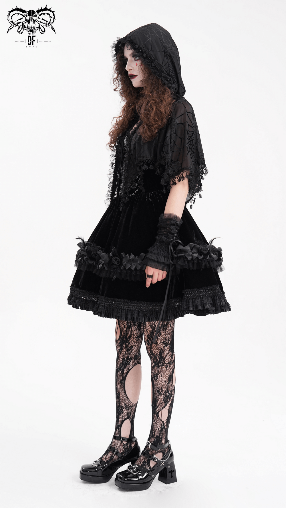 Gothic lace cape with hood and tassels, paired with a black dress and fishnet stockings for a stylish dark look.