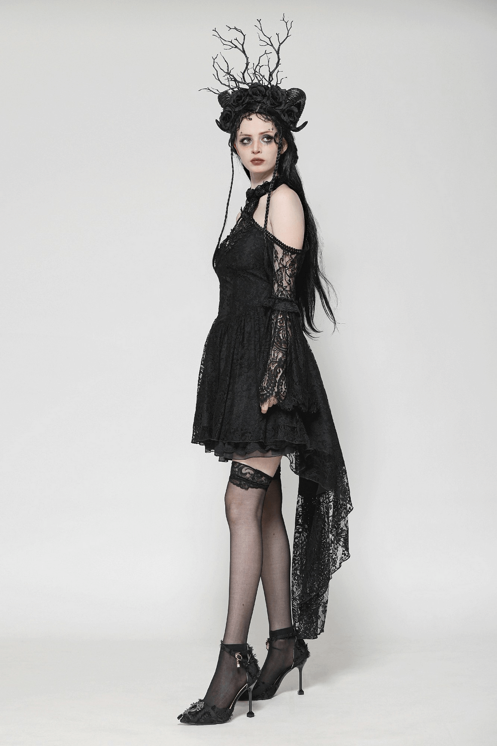 Model in black gothic lace cutout dress with heart detail, ruffled hem, and open shoulders, showcasing a dramatic vibe.