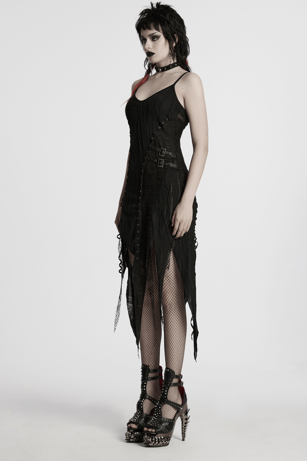 Black gothic lace dress with asymmetric hem and eyelets, styled with fishnet stockings and edgy heels.