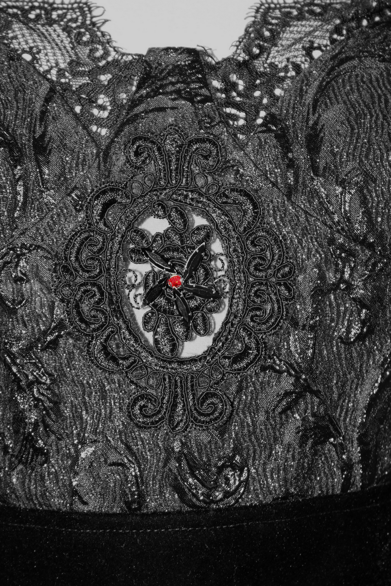 Close-up of intricate black lace with a gothic red beaded design on a sleeveless dress.