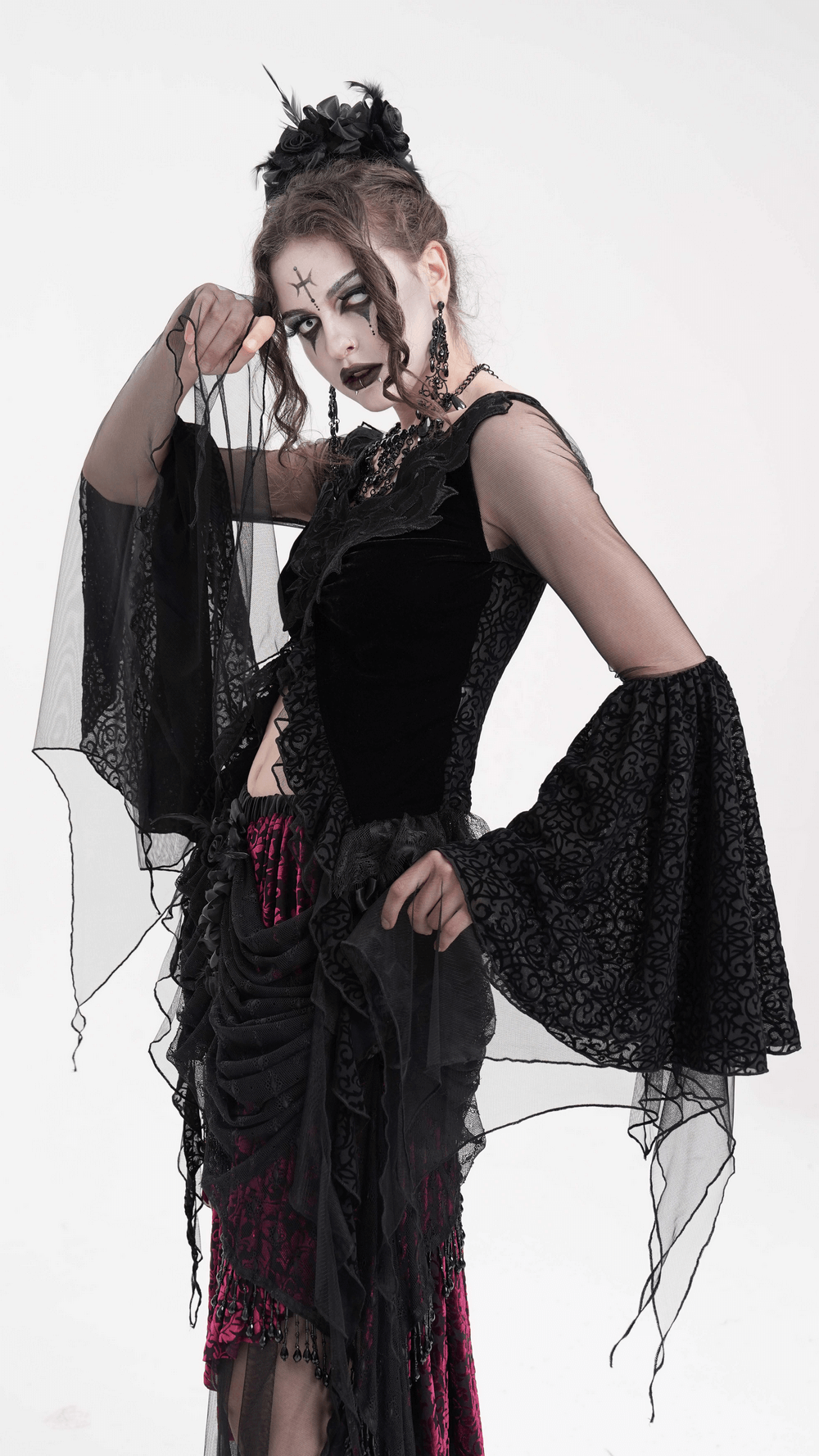 Gothic model wearing a black lace top with dramatic mesh sleeves and intricate floral details.