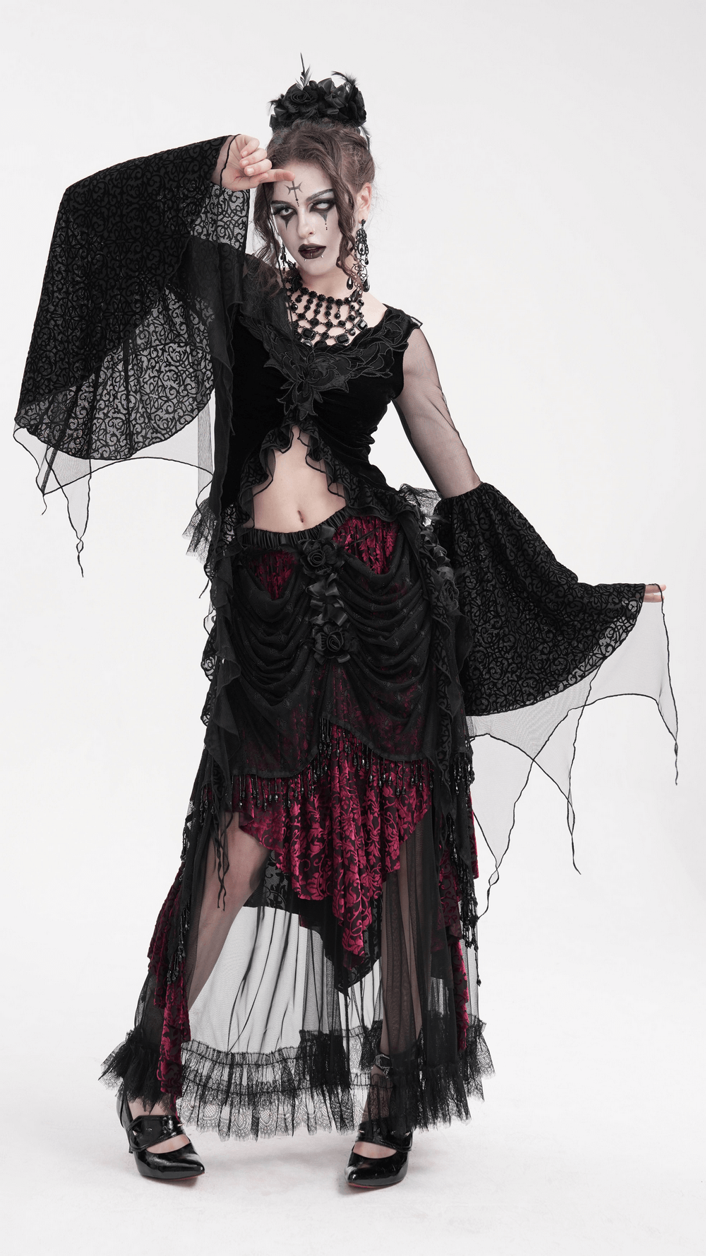 Gothic lace top with bell sleeves, layered skirt, and dramatic makeup in a dark fantasy ensemble.