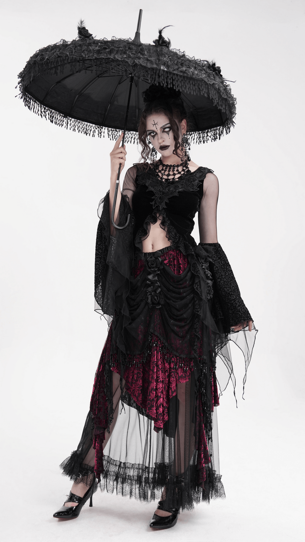Gothic fashion model in black lace top holding a black parasol, showcasing a dramatic medieval-inspired look.