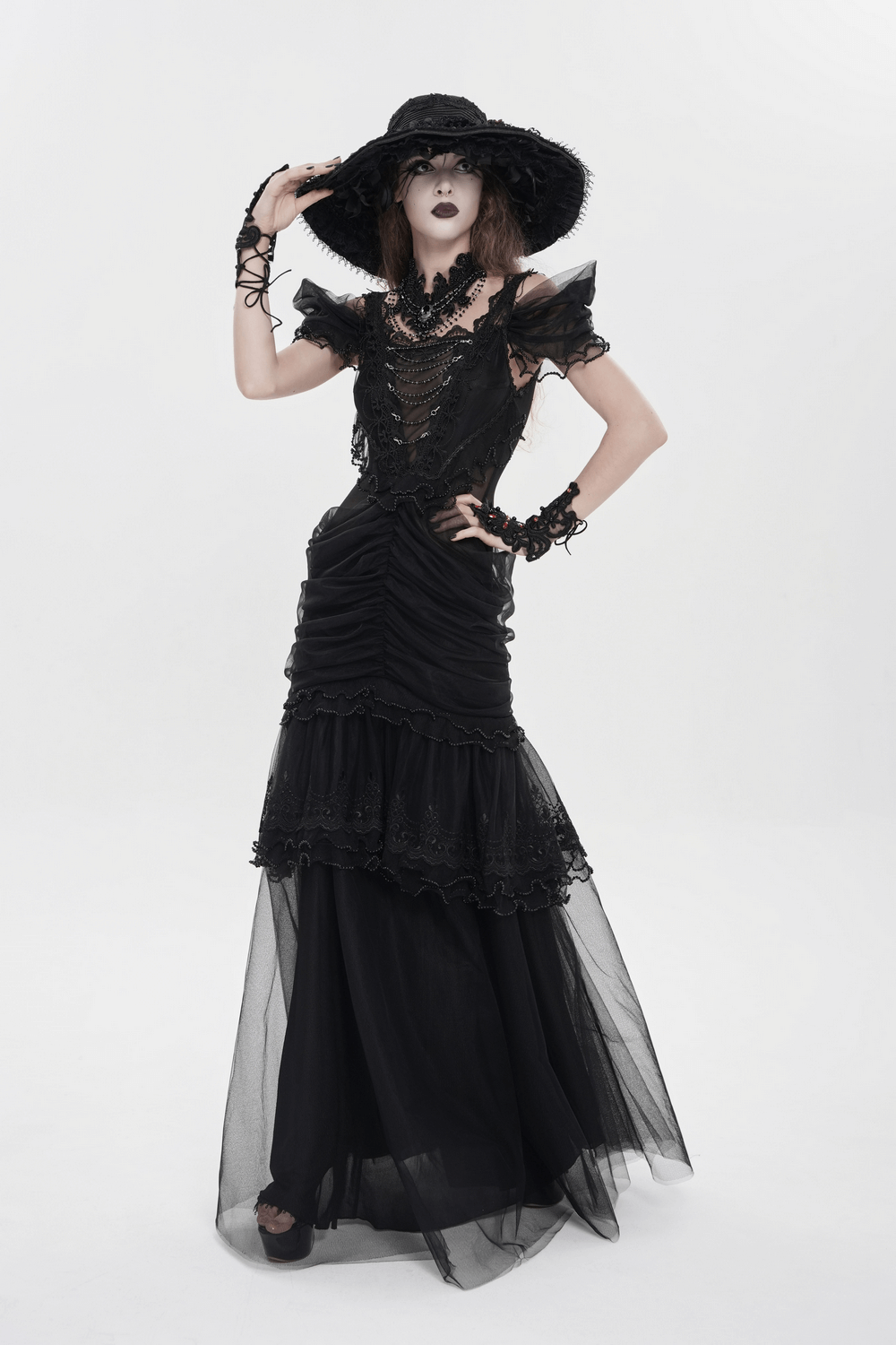 Black Gothic Lace-Up Dress with Ruffled Tulle and Roses worn with a large black hat and dramatic accessories.