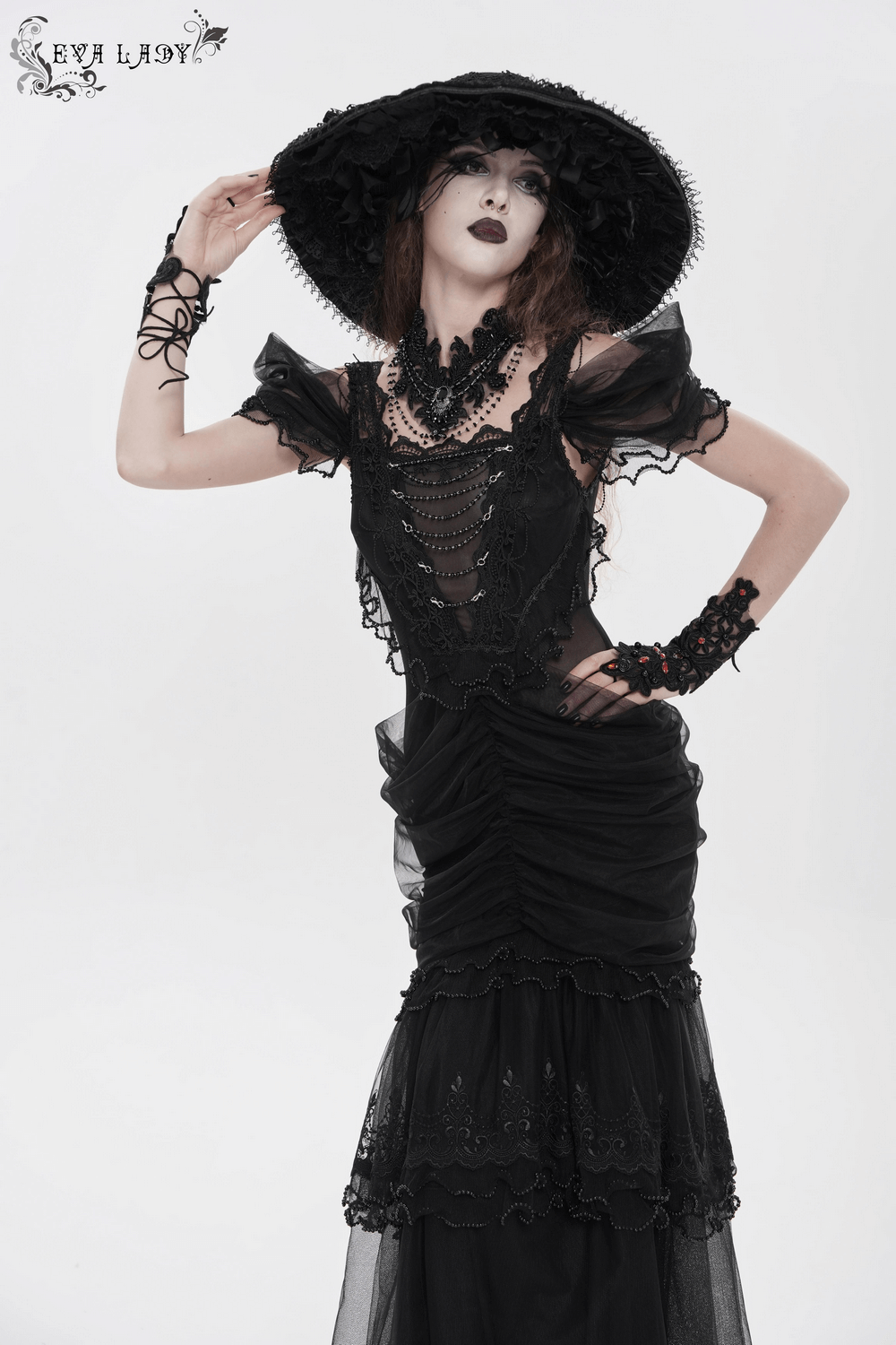 Black Gothic Lace-Up Dress with Ruffled Tulle and Roses displayed on a model wearing a dramatic hat and accessories.