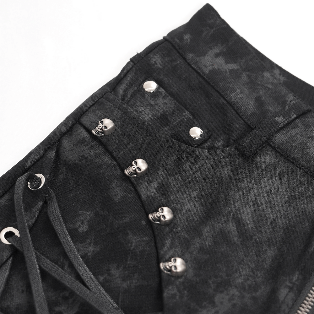 Close-up of black gothic lace-up pants with skull detailing and pentagram charm, showcasing edgy fashion style.